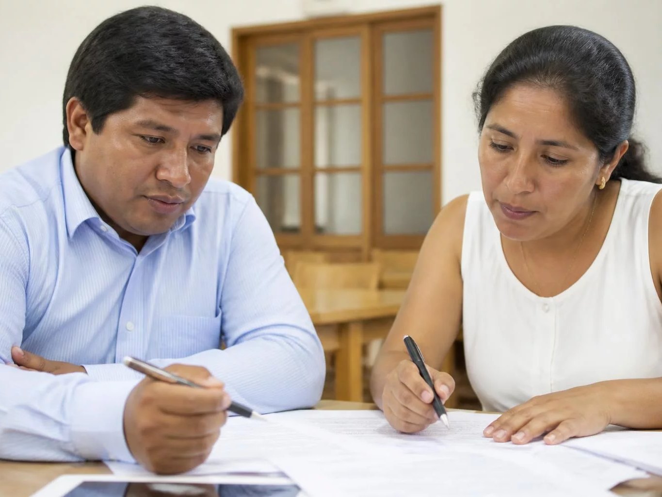 Dos asistentes en la mesa de trabajo, entre hojas y anotaciones